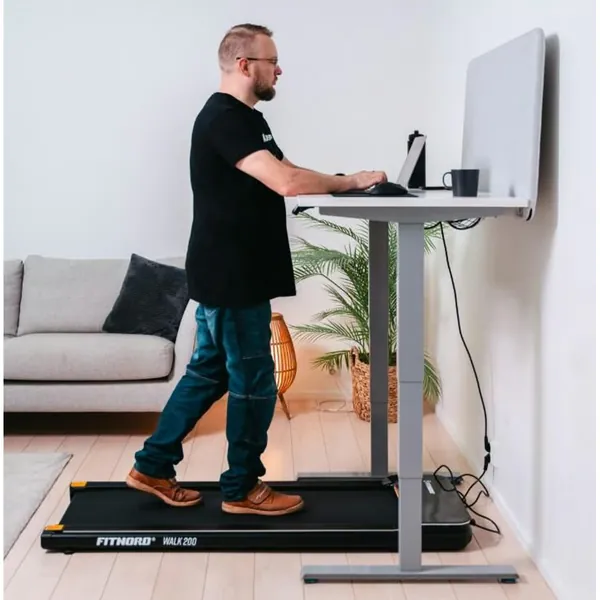 FitNord Walk 200 VOITELUVAPAA -kävelymatto korkeussäädettävän työpöydän alla kotitoimistossa aktiiviseen työskentelyyn ja päivittäiseen kävelyyn.